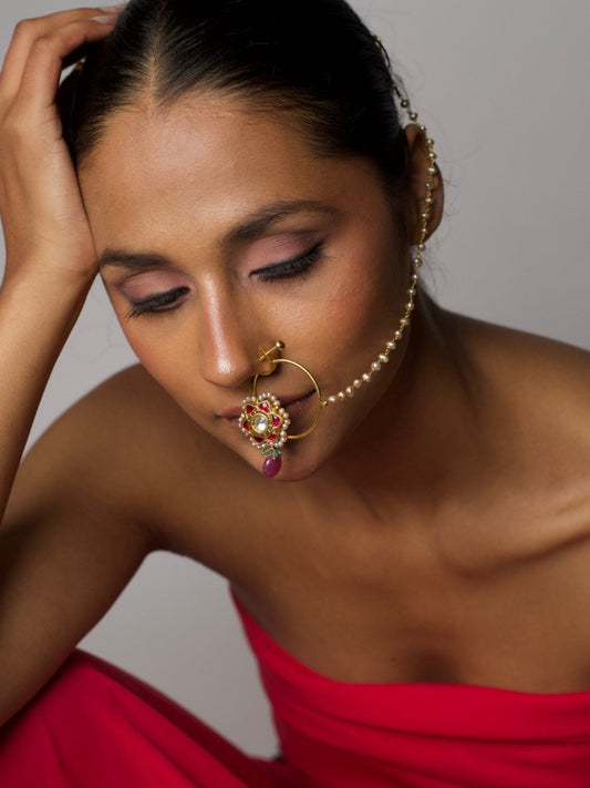 Close-up of woman wearing The Reclaimed Rose Nath – a non-pierced 92.5 silver nose ring with pink kundan floral setting, gold polish, and pearl chain