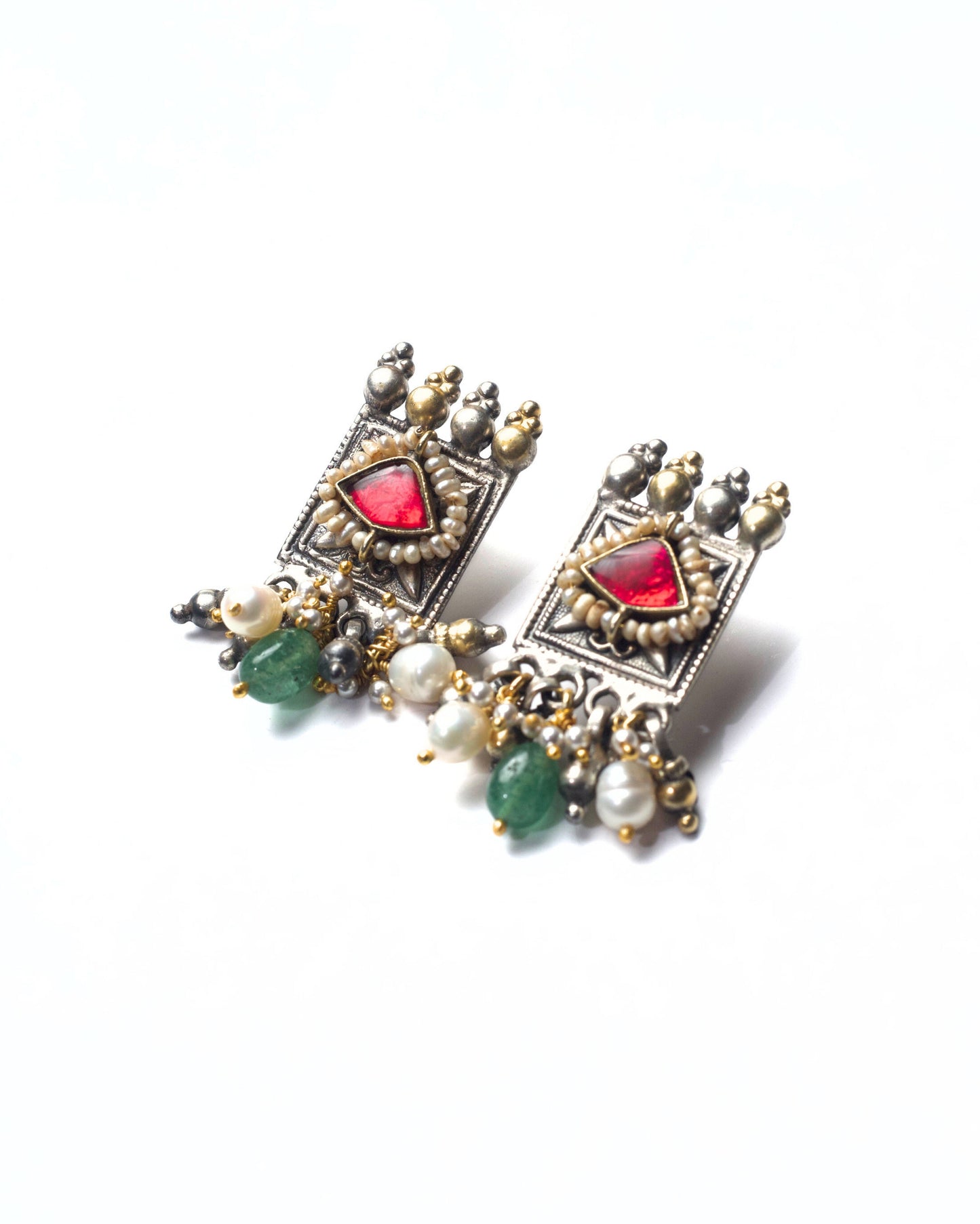 Side shot of square framed fusion silver stud earrings in 925 silver with deep red stone, pearl detailing, oxidised finish, and subtle gold-polished accents.