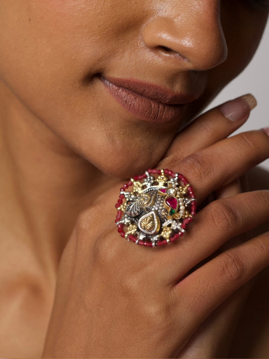 Close-up of Mayura Chakra Ring by Naksa, a handcrafted 92.5 silver ring featuring a sculpted peacock, red beaded border, gold and silver floral elements.