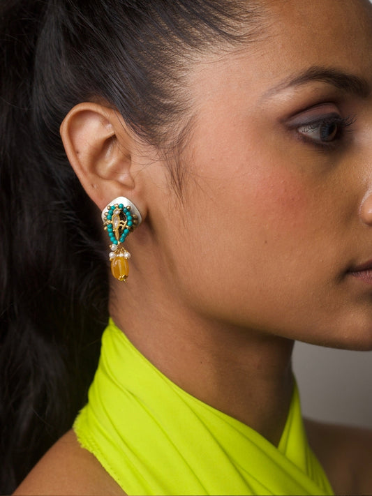 Close-up of a woman wearing Naksa’s Everyday Amalfi Drops – handcrafted 925 silver earrings with turquoise beading, gold motif, and yellow stone drop, styled for daily wear.