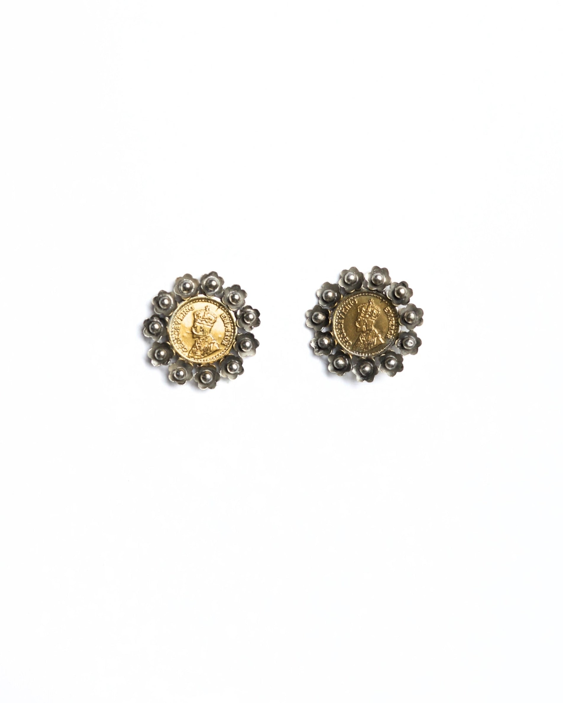 Close-up of dual-tone 925 silver stud earrings featuring an embossed vintage coin centre with oxidised floral petal border and bead detailing.