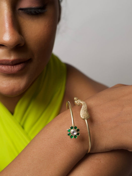 Close-up of a 92.5 silver open cuff bracelet featuring a sculpted peacock motif and green enamel flower, worn on wrist.