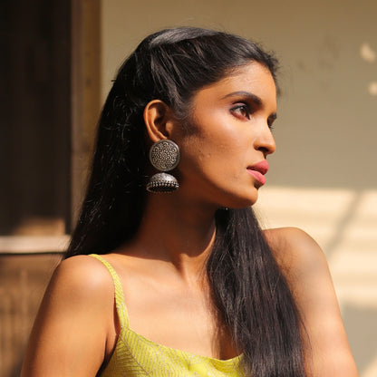 Oxidised 925 silver jhumkas with intricate floral details, lightweight and perfect for fusion wedding outfits.