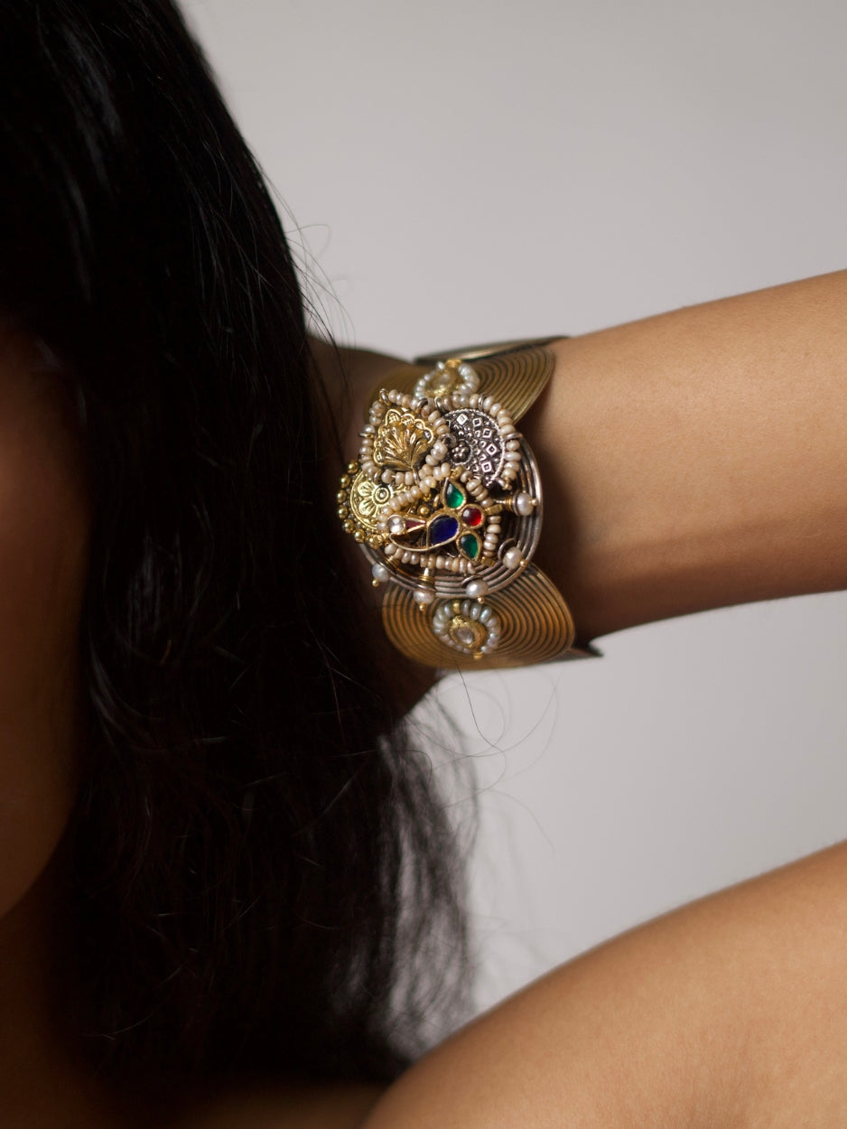 Handcrafted silver cuff with spiral base, navratna enamel, and sculptural motifs in 92.5 silver by Naksa