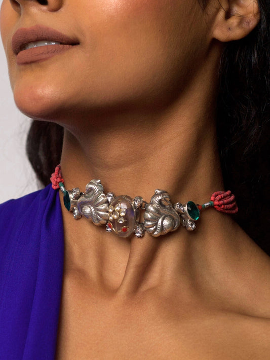 Close-up of She Who Blooms Silver Choker featuring oxidized silver floral motifs, central gemstone detail, and red thread tie-up, styled on model’s neck.